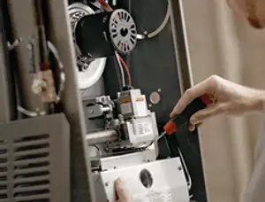 Furnace repair technician inspecting internal components and wiring in Arlington, TX