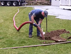 Septic pumping technician servicing a residential septic tank with a vacuum hose in Arlington, TX