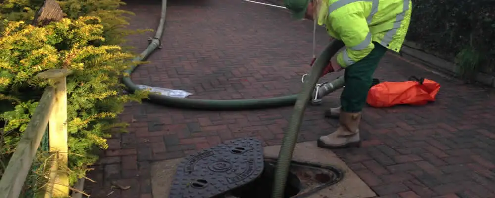 Septic tank cleaning technician servicing a septic tank with a vacuum hose in Arlington, TX