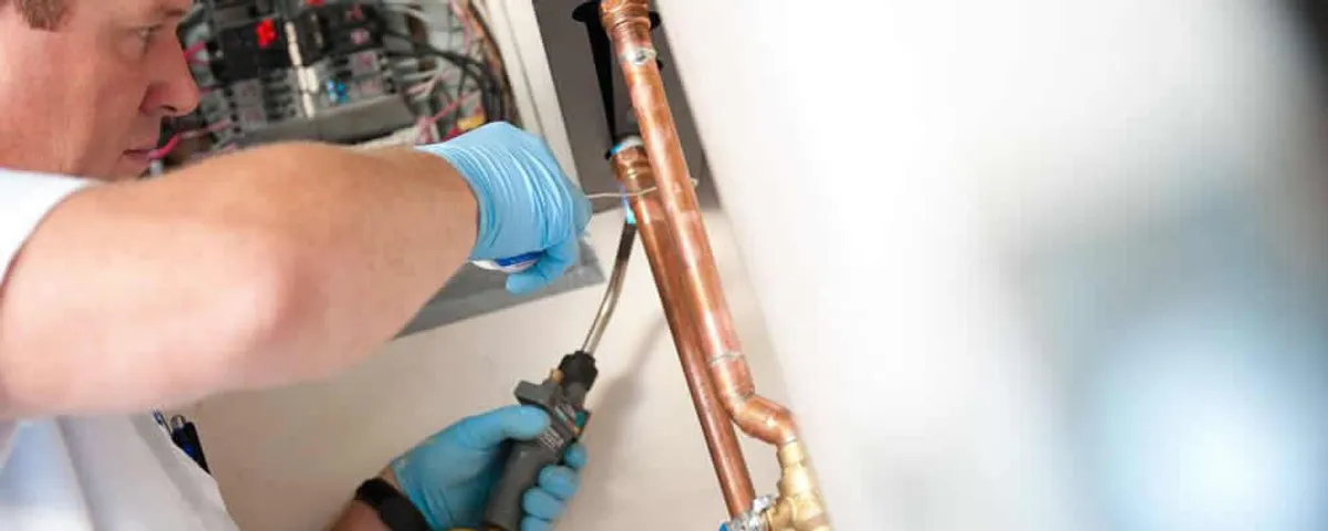 Water heater repair technician testing copper pipe connections and controls in Arlington, TX